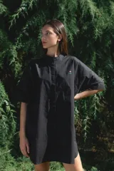 Camisa negra de algodón con cuello mao y mangas cortas. Presenta un pequeño bordado de una flor blanca en el pecho.