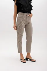 Jean gris lavado, estilo mom fit, con aplique fruncido en forma de espiral en la pierna izquierda, tiro alto, bolsillos delanteros y traseros funcionales, y cierre frontal con botón y cremallera.