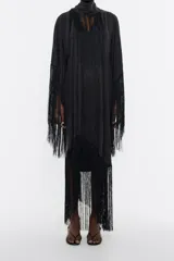 Vestido largo negro de lyocell con corte oversize, escote en V pronunciado, manga corta murciélago con maxiflecos, pieza extraíble para el cuello con flecos y bajo con maxiflecos.