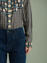 Camisa marrón con diseño a cuadros en tonos celeste y naranja, con cuello clásico, cierre frontal con botones plateados y mangas largas.