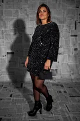 Vestido corto negro con lentejuelas, de mangas largas y escote redondo.