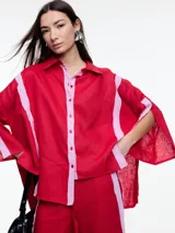 Camisa de lino color negro con silueta amplia y mangas 3/4. Diseño con tiras de color blanco en contraste en la cartera, mangas y cuerpo. Tiene tajos laterales y ruedo irregular en el frente.