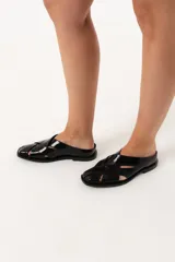 Zueco negro de cuero con capellada enrejillada y horma cuadrada.