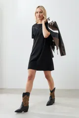 Vestido corto negro con flecos en el pecho y tachas plateadas en los hombros.