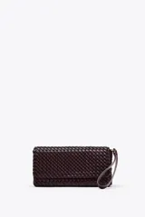 Bolso alargado color marrón oscuro con diseño trenzado, asa de mano y bandolera. Cierre con solapa y botón imantado, bolsillo interior.
