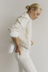 Chaqueta color blanco con bordado floral, cuello camisero, cierre frontal con botones y mangas largas.