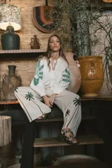 Pantalón de lino color crudo con corte amplio y estampado de palmeras en la parte inferior de las piernas.