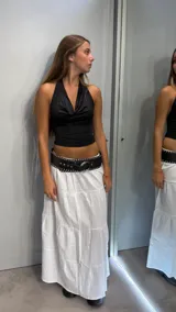 Top negro ajustado al cuerpo con escote halter y efecto drapeado en el busto.