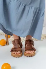 Sandalias de cuero marrón con tiras anchas y hebillas ajustables. Suela gruesa con diseño dentado.