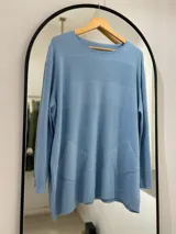 Sweater celeste de punto con cuello redondo, corte holgado, mangas largas y bolsillos delanteros.
