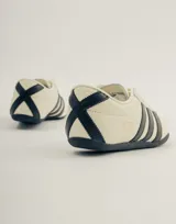 Championes Adidas Tokyo color crema con detalles en negro, con las tres tiras características de la marca en los laterales.