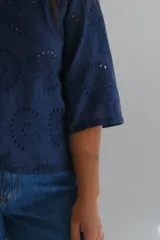 Blusa azul marino con bordado calado, escote cuadrado y mangas 3/4 acampanadas.