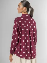 Camisa de manga larga en fibrana color bordó con estampado de lunares grandes en color crema. Presenta cuello camisero y cierre frontal de botones.