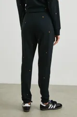 Pantalón de jogging negro con estrellas doradas estampadas, cintura elástica con cordón ajustable y puños elásticos.