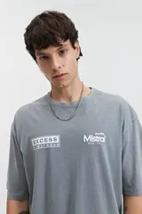 Remera gris de manga corta con corte oversize, cuello redondo y estampado frontal con los logos de Mistral y Excess Streetwear.