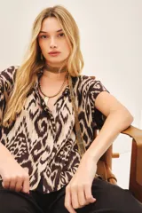 Camisa de corte amplio con estampado ikat en tonos beige y marrón. Tiene cuello camisero, manga corta y botones ocultos.