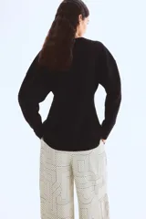 Pantalón de corte amplio y tiro alto, con cintura elástica y cordón de ajuste. Presenta un estampado geométrico en blanco y negro con líneas finas y formas entrelazadas.