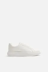 Zapatillas deportivas blancas, de estilo minimalista, con cordones y suela gruesa.