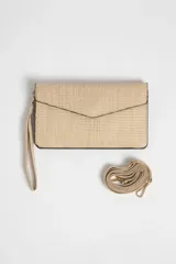 Billetera tipo sobre color beige con textura tejida y correa larga fina del mismo material.