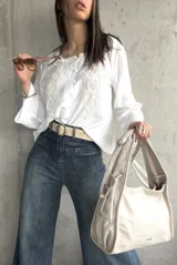 Blusa blanca de manga larga acampanada con bordado floral en el frente y cierre con botones.