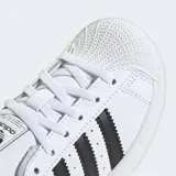Zapatillas Adidas Superstar blancas con las tres tiras laterales en negro y puntera de goma.