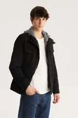 Campera militar negra con capucha gris de algodón, cierre frontal con cremallera y botones a presión, cuatro bolsillos frontales con solapa y charreteras en los hombros.