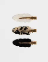 Set de tres hebillas para el pelo con forma ondulada. Incluye una hebilla blanca nacarada, una hebilla carey y una hebilla negra.