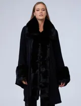 Ruana tejida color crema de la marca Adrienne Vittadini, con cuello, delantera y puños con aplique en símil piel. Delantera con abertura central y botón trenca.