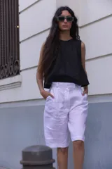 Bermuda blanca de lino, corte sastre, tiro alto, largo a la rodilla y bolsillos laterales.