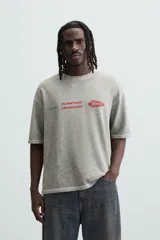 Camiseta gris de punto con cuello redondo y manga corta. Estampado combinado a contraste en delantero y espalda con la frase "Planetary Connection" y un diseño abstracto en rojo.
