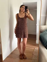 Vestido corto de tejido de punto color beige/dorado, con escote redondo y tirantes anchos. Presenta un tejido acanalado verticalmente con hilos de lurex que le dan brillo.