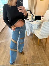 Pantalón de jean azul con corte holgado y apliques de gamuza marrón bordados a mano en los laterales.
