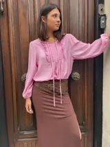 Blusa rosa de mangas largas con puños elásticos, escote en V con volados y lazos.