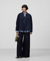 Pantalón de denim azul oscuro de pierna ancha, tiro alto, cinco bolsillos, pespuntes a contraste y bajos sin dobladillo.