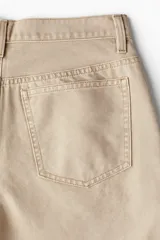 Pantalón de lona color beige, de corte holgado con pierna ancha y cinco bolsillos.