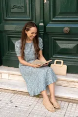 Vestido midi de poliéster y algodón, color verde azulado con estampado floral blanco, corte recto, mangas cortas con volados y cuello redondo.