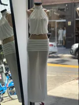 Conjunto de top halter y falda larga, ambos de tela traslúcida color blanco.