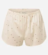 Conjunto de pijama compuesto por un top de satén color crema con lunares marrones, breteles finos regulables y escote en V con encaje, y un short con cintura elástica y estampado de lunares a juego.