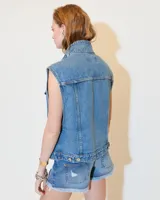 Chaleco de denim celeste con cuello alto, mega sisa y corte boxy. Tiene bolsillos plaqué en el pecho, bolsillos ojal en los laterales y presillas en el ruedo trasero para ajustar.