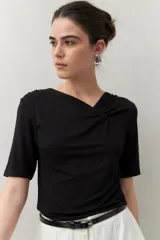 Remera negra de modal de manga corta con cuello asimétrico y detalle de nudo con frunces.