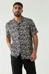 Camisa estampada de hombre, corte slim, manga corta, cartera abotonada y logo bordado.