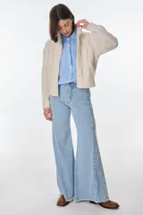 Cardigan color crudo de tejido de punto con diseño trenzado, cuello alto y cierre frontal con cremallera.