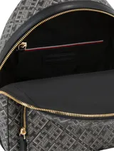 Mochila Tommy Hilfiger confeccionada en poliuretano con estampado integral de monograma TH. Presenta un compartimento principal con cierre, un bolsillo frontal con cremallera y herrajes metálicos dorados, incluyendo el logo de la marca en el frente. Cuenta con correas de hombro ajustables y un asa superior.