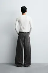 Pantalón de jeans de algodón, corte baggy fit, tiro medio, con efecto lavado en tonos grises y verdes. Presenta cinco bolsillos y cierre frontal con cremallera y botón.