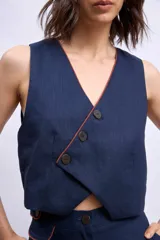 Chaleco color crudo con cuello en V y botones frontales.