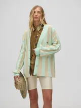 Cardigan a rayas horizontales en tonos beige y negro, de corte holgado y abierto, con botones metálicos y logo MUTMA bordado en el frente.
