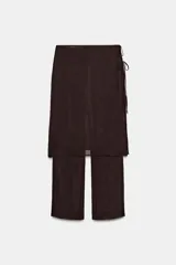 Conjunto de pantalón ancho marrón oscuro con una sobrefalda envolvente (tipo pareo o falda cruzada) que se ata con lazadas finas en el lateral.