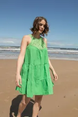 Vestido corto color naranja con escote halter de crochet tejido en hilo de algodón y falda escalonada.