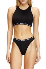 Conjunto de ropa interior Diesel color negro, compuesto por un corpiño deportivo con cuello alto y una tanga. Ambos tienen una banda elástica blanca con el logo de la marca.