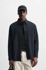 Camisa azul marino de algodón con textura jacquard, corte relaxed fit, cuello solapa, manga larga con puños abotonados y cierre frontal con botones.